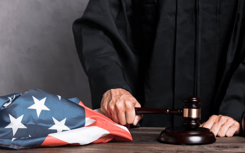 close up judge with flag striking gavel (2)